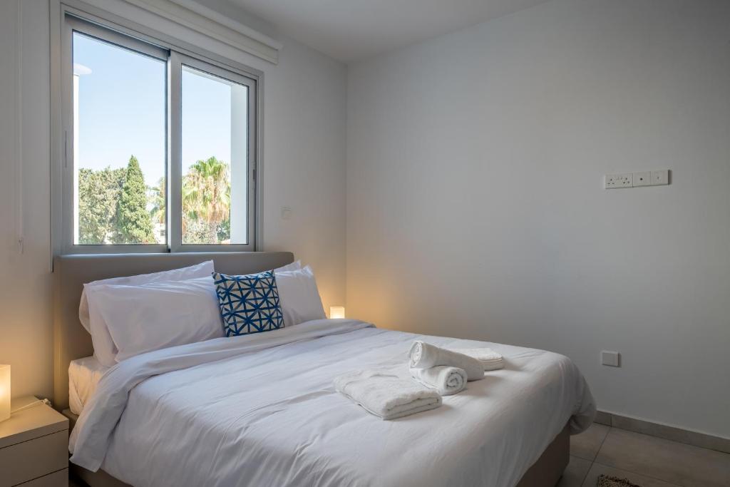 een slaapkamer met een wit bed en 2 handdoeken bij Solaar Apartments Faneromeni in Larnaka