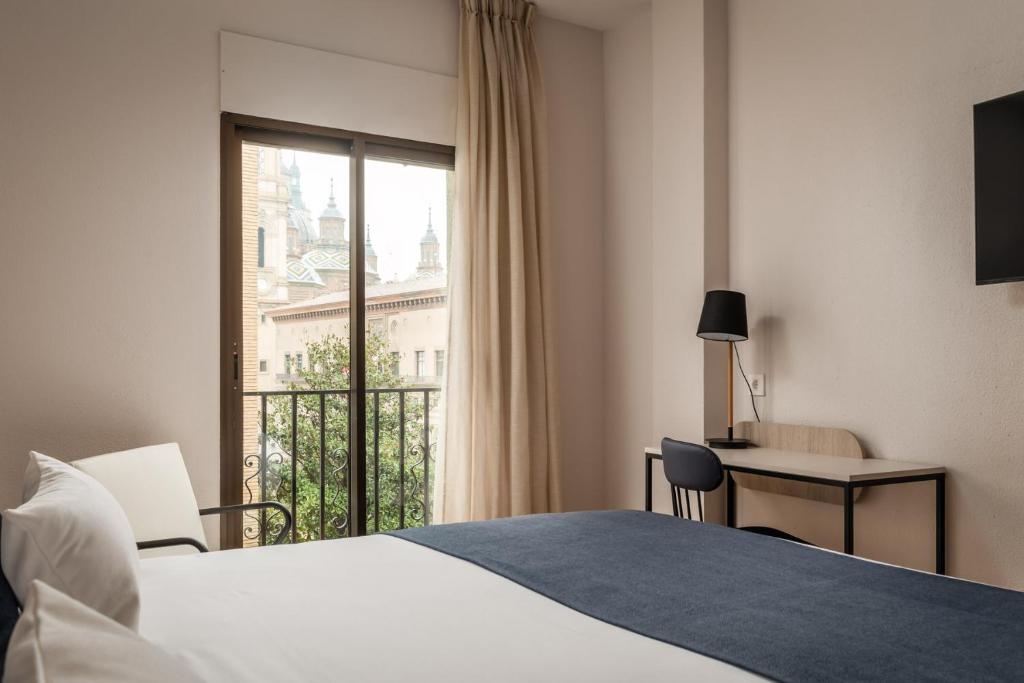 ein Hotelzimmer mit einem Bett und einem Fenster in der Unterkunft Hotel Don Jaime 54 in Saragossa