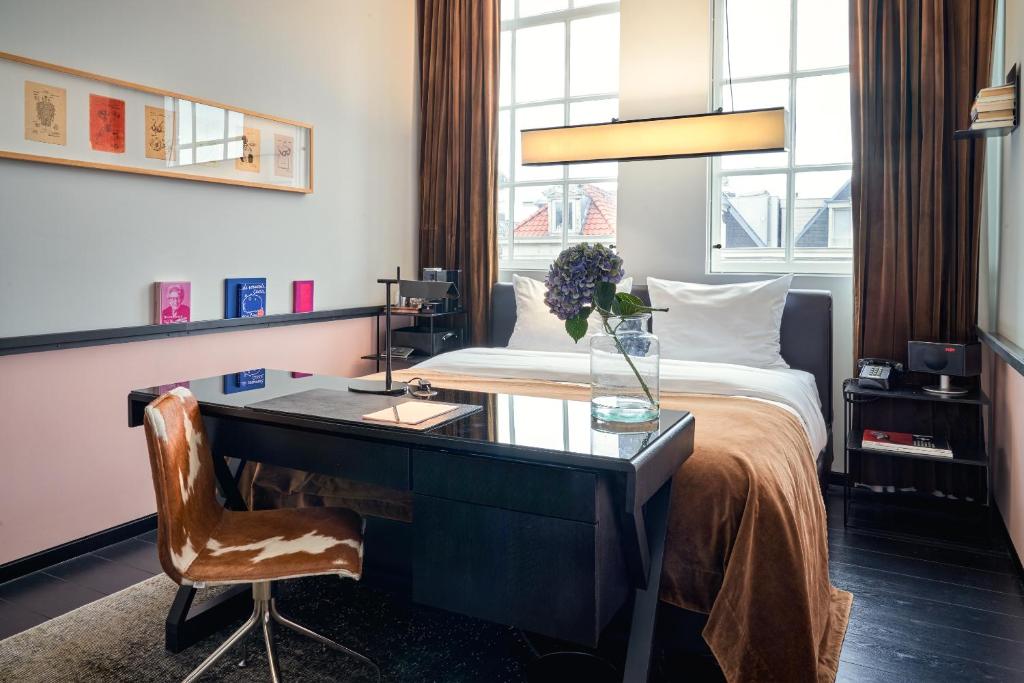 Sir Albert Hotel, part of Sircle Collection في أمستردام: غرفة في الفندق مع مكتب وسرير