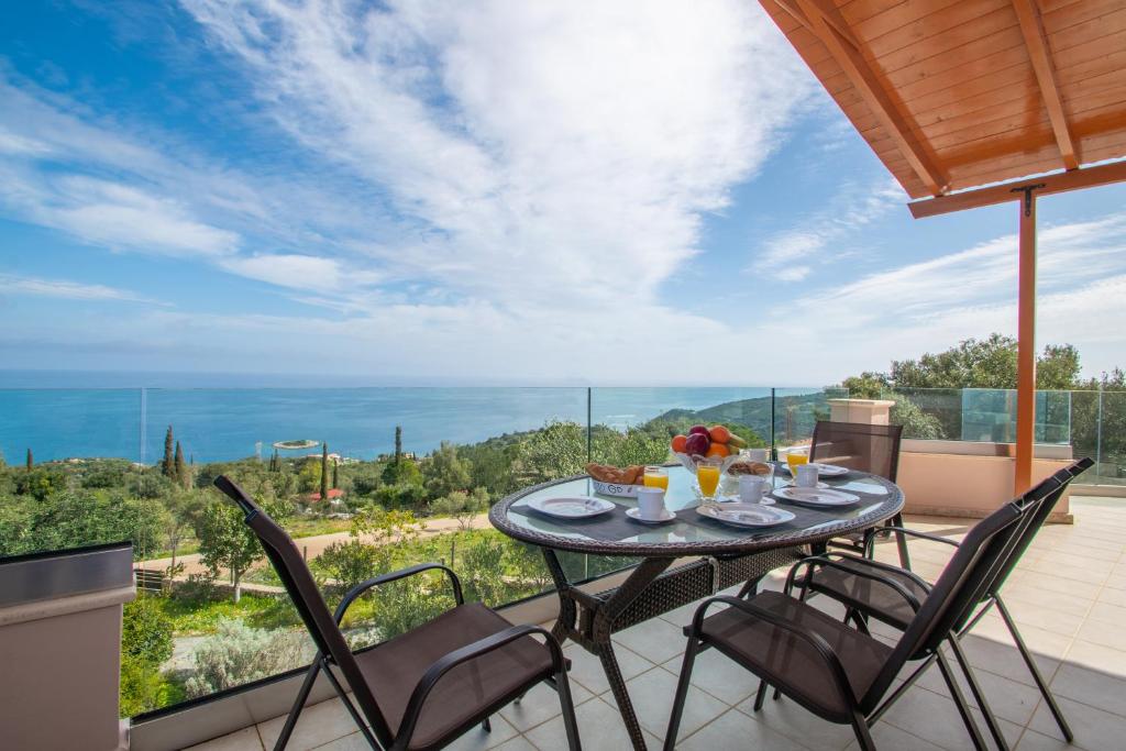 DN Beach Coast Villa في Skinária: طاولة وكراسي على شرفة مطلة على المحيط