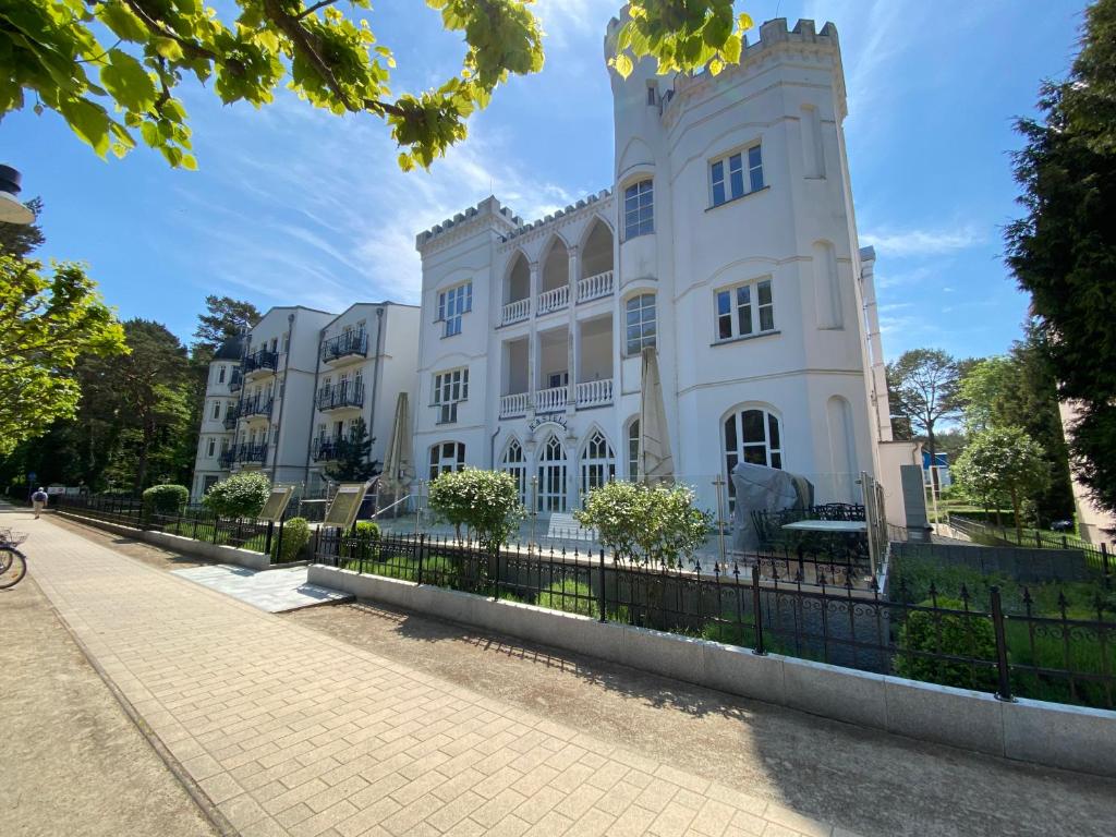 un edificio bianco con una recinzione di fronte di Haus Kastell - Ferienwohnung 113 a Ahlbeck