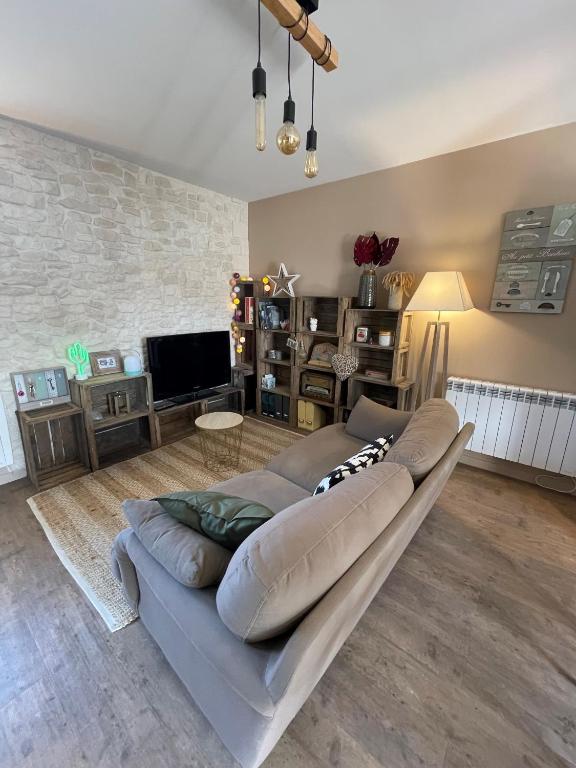ein großes Sofa im Wohnzimmer mit einem TV in der Unterkunft La Maison de Fanny in Vineuil