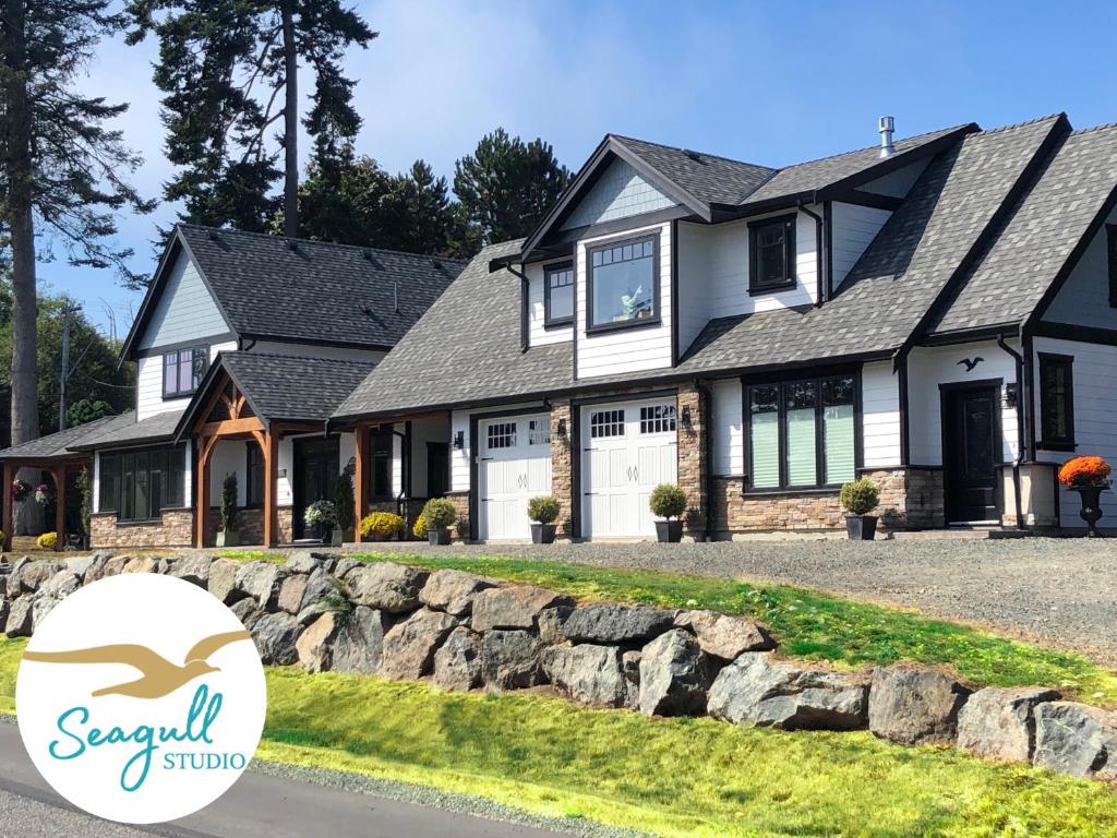 a house with a stone wall in front of it at Seagull Studio Vacation Suite in Sooke