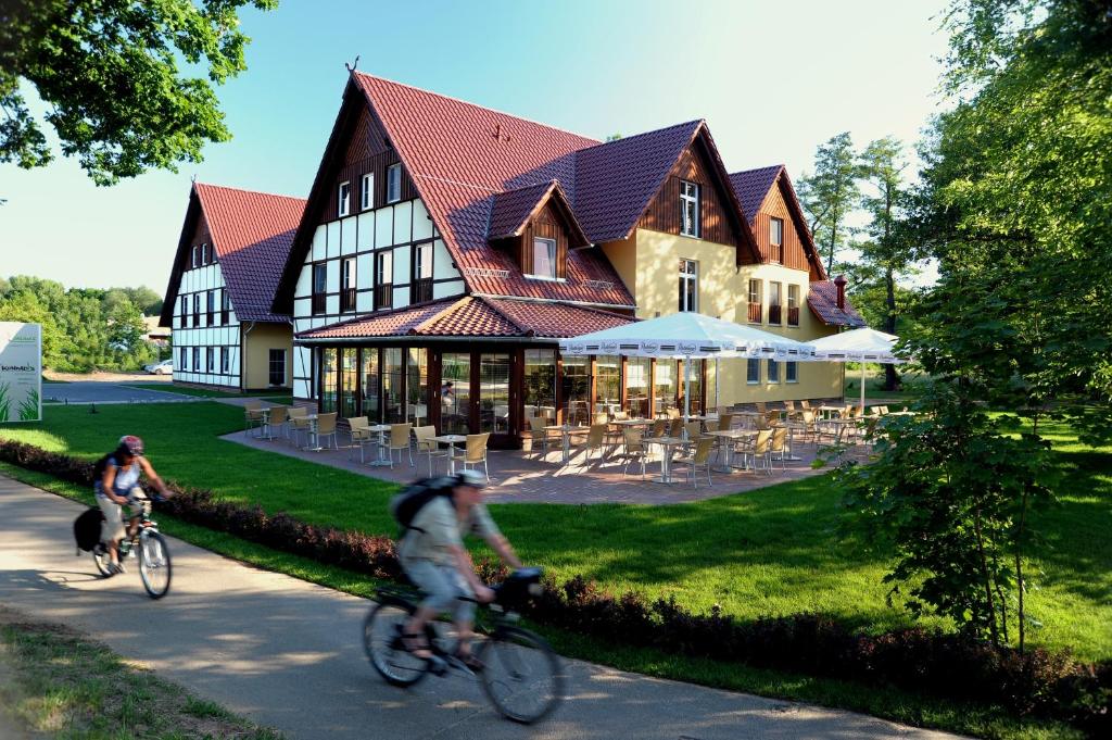 zwei Personen, die vor einem Gebäude Fahrrad fahren in der Unterkunft Kur und Wellnesshaus Spreebalance, The Originals Relais (Relais du Silence) in Burg