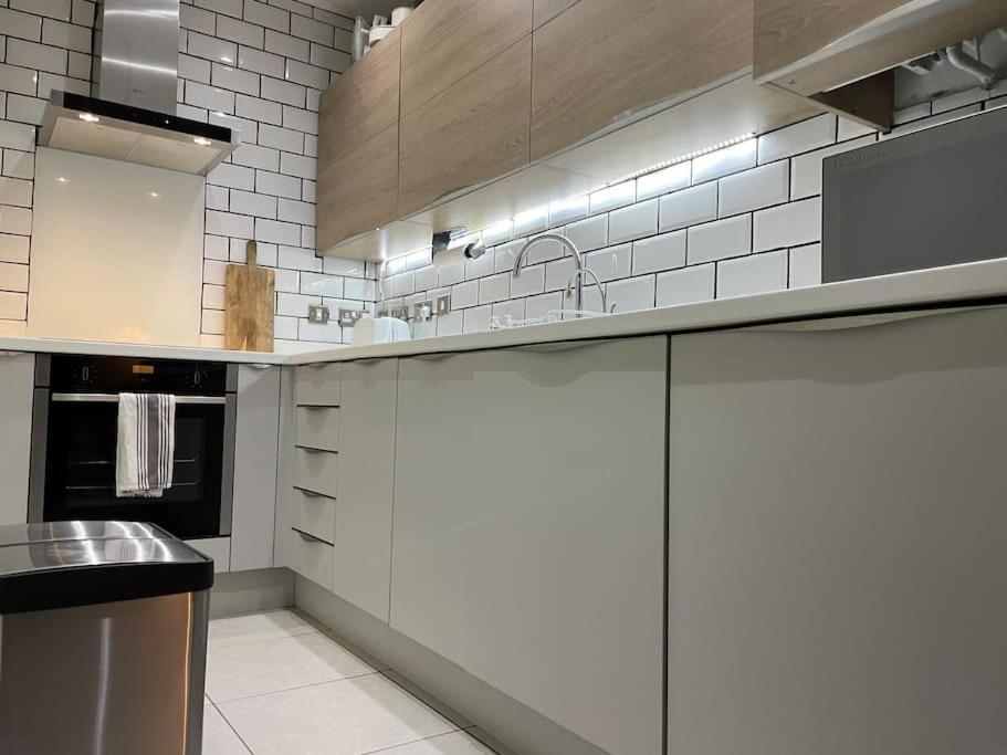 a kitchen with white appliances and white tiles at The Flat on Humber Street in Hull