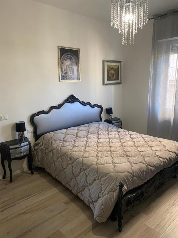 um quarto com uma cama grande com duas mesas e um lustre em Appartamento Valentina em San Vincenzo
