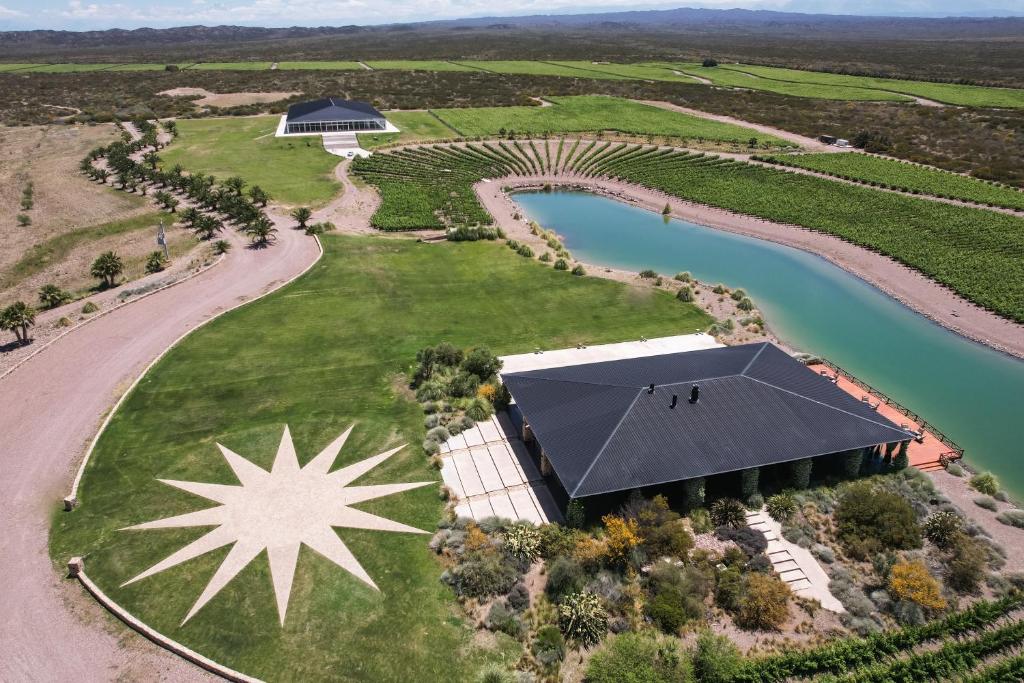 an aerial view of a vineyard with a building and a river at Villas Del Malbec Lodges in Agrelo