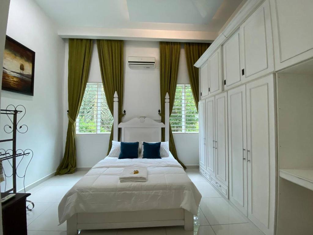 1 dormitorio con cama blanca y almohadas azules en VILLA PERMATA IBU en Jeram