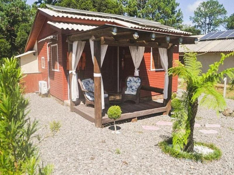 ein Haus mit einem Pavillon und einem Stuhl im Hof in der Unterkunft RECANTO DO SINALEIRO GRAMADO in Gramado