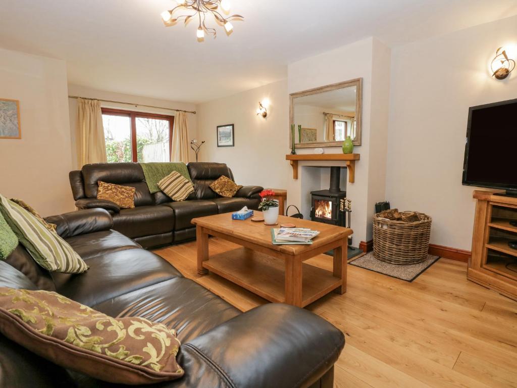 a living room with leather couches and a coffee table at Ash Gill Cottage in Coniston