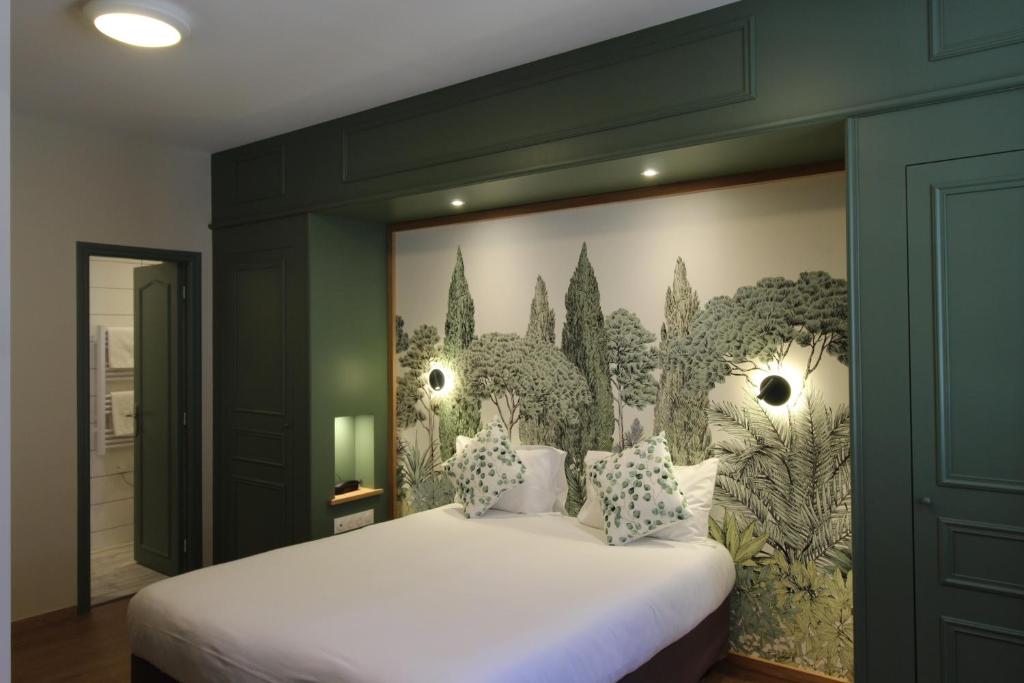 a bedroom with a large white bed with a wall at Garlande Hôtel Avignon Centre in Avignon