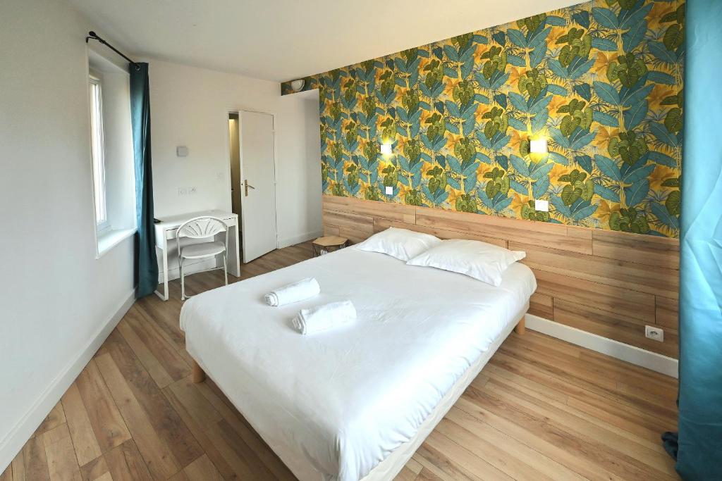 um quarto com uma grande cama branca e papel de parede floral em Cit'Hôtel La Résidence em Villebois