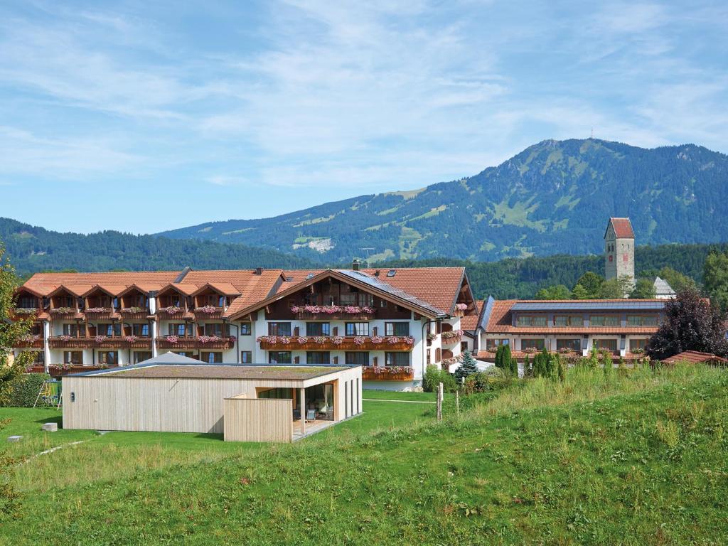 a large building in a field with mountains in the background at Hotel "Krone" - Immenstadt-Stein in Immenstadt im Allgäu