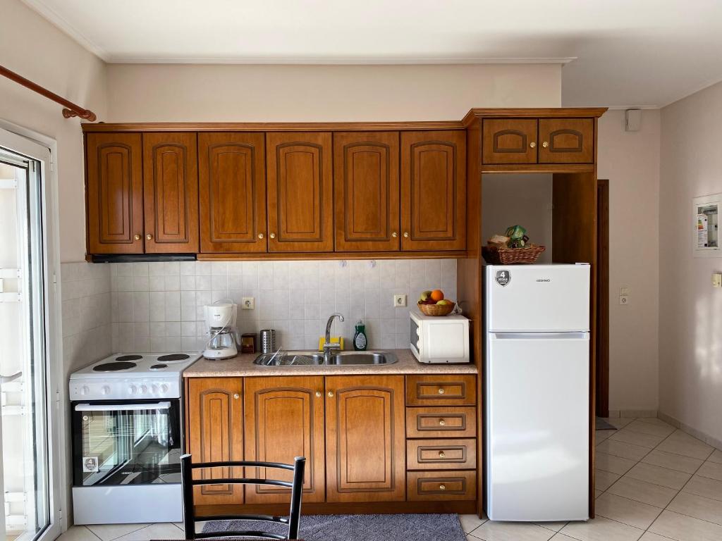 a kitchen with wooden cabinets and a white refrigerator at Αρτέμιδα Karpenisi Apartment in Karpenisi