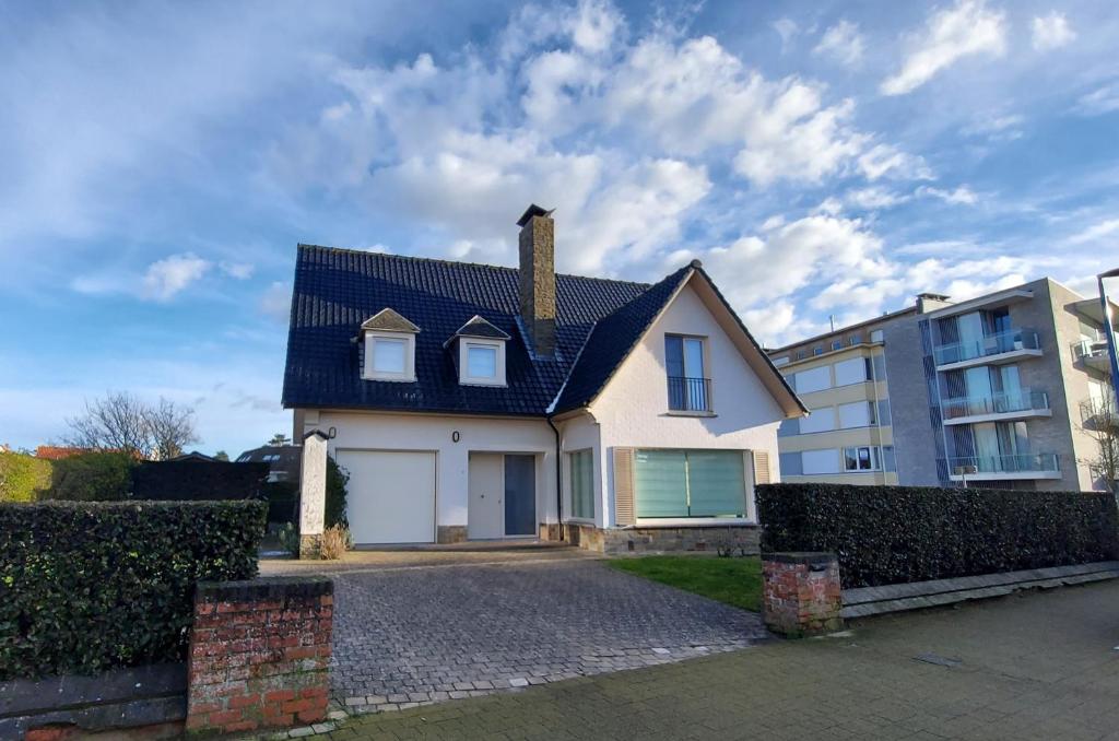 a white house with a black roof at Villa Duinberg R-002 in Koksijde
