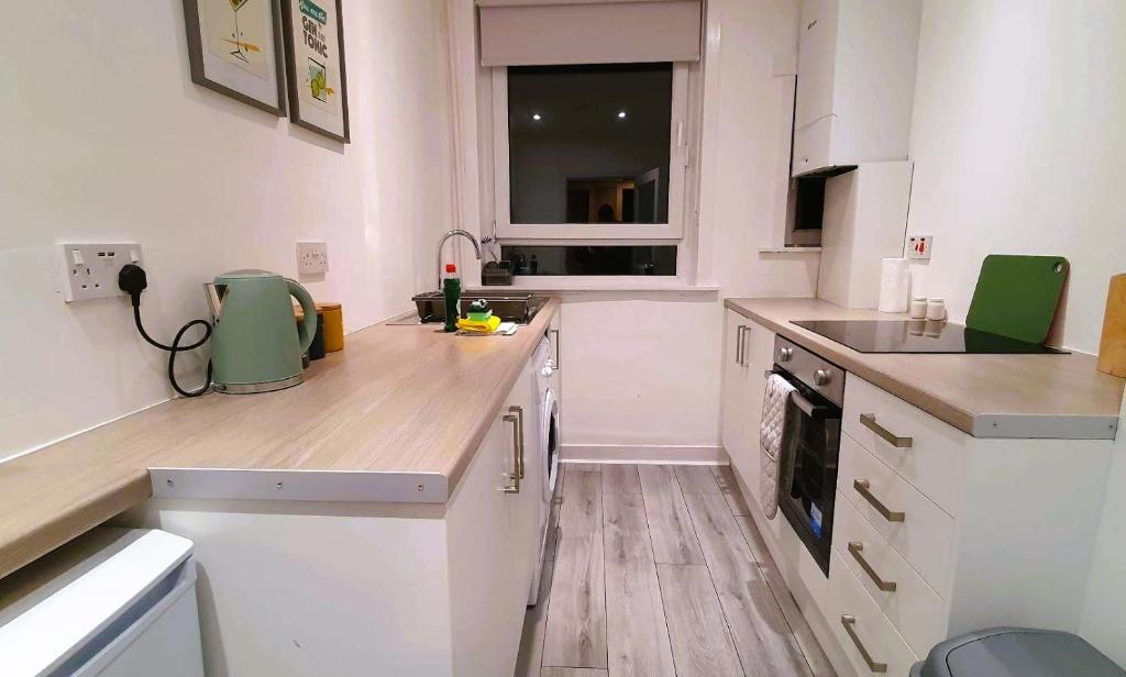 a kitchen with white cabinets and a wooden counter top at Mackie House in Port Glasgow