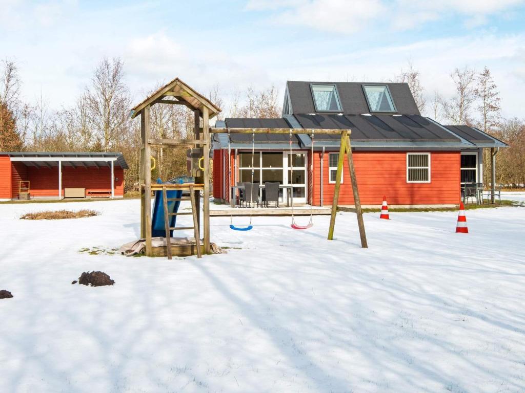 un parque infantil en la nieve frente a una casa en Holiday home Vemb VI en Vemb