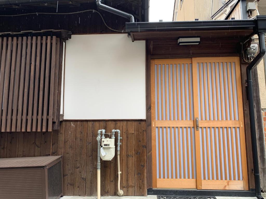 翠云間 庭院式京町屋 京都四条西院 في كيوتو: مبنى عليه بابين وعلامة بيضاء
