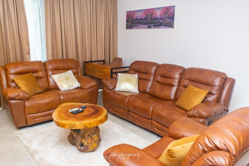 a living room with brown leather furniture and a table at Luxury 2 Bedroom Apartment with Huge Balcony , Pool, Gym at Tribute House in Accra