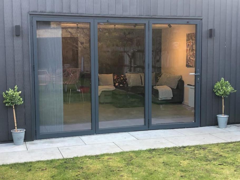 un porche cubierto con puertas de cristal en una casa en Brand new studio outhouse Putney SW15 en Londres