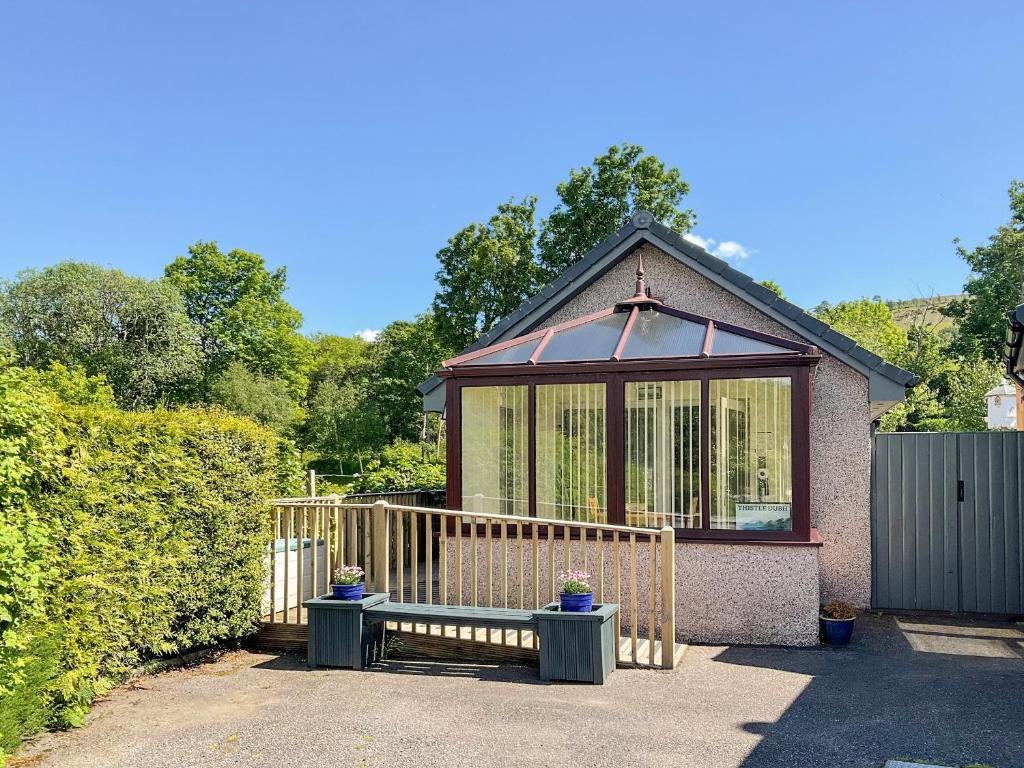 ein kleines Haus mit einer Bank davor in der Unterkunft Thistle Dubh in Drumnadrochit