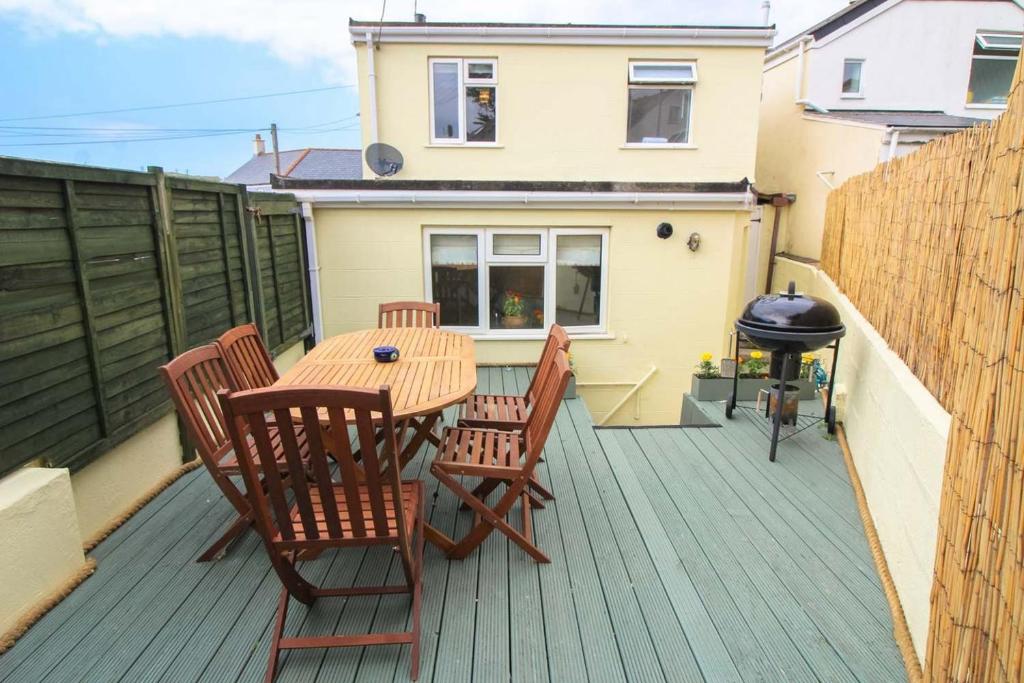 a wooden table and chairs on a deck with a grill at Sunny Corner Cottage in Hayle