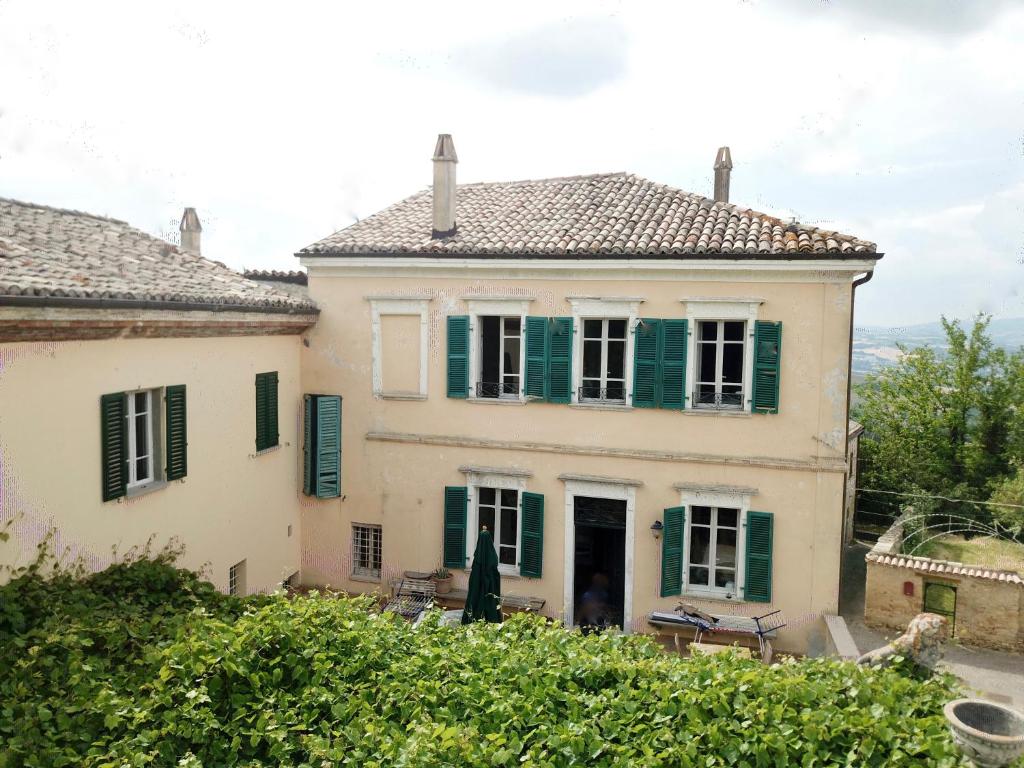 a large white house with green shutters at Palazzo Minzoni in SantʼIppolito