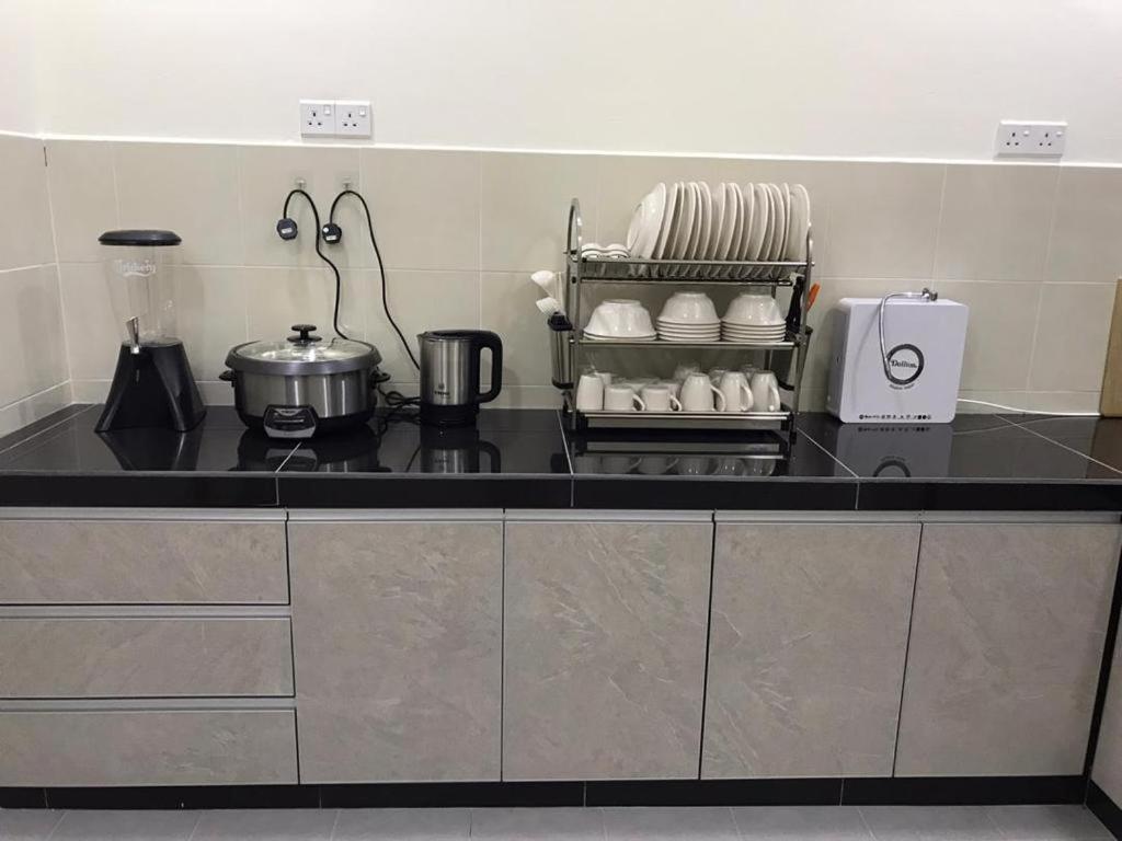 eine Küche mit einer schwarzen Arbeitsplatte mit Geschirr darauf in der Unterkunft 88 Cozy House in Kuala Selangor