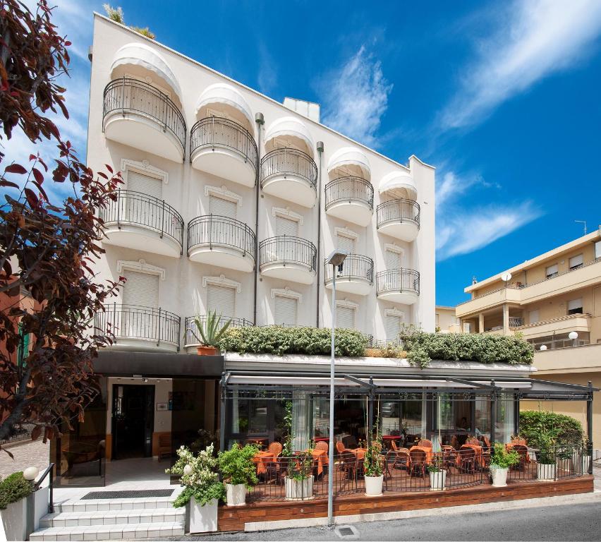a large white building with terraces on it at Hotel Gabriella in Rimini