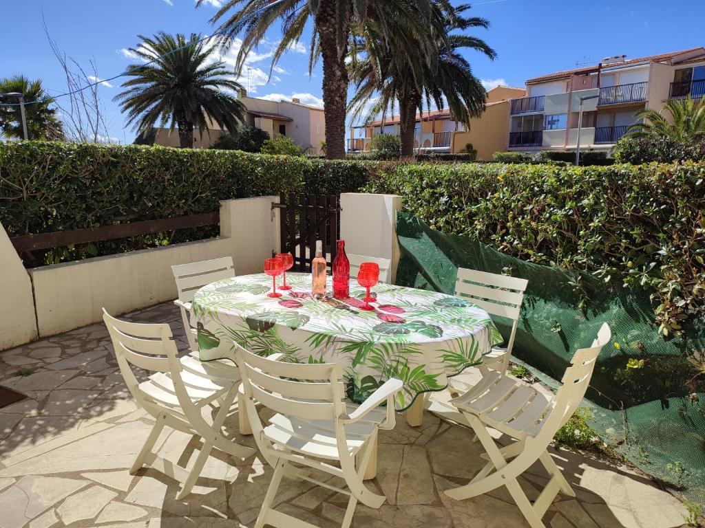 stół z krzesłami i kieliszki do wina na patio w obiekcie AQUAPLAGE Joli appartement RDC piscine 1 ère ligne mer Richelieu Cap d'Agde w Cap d'Agde