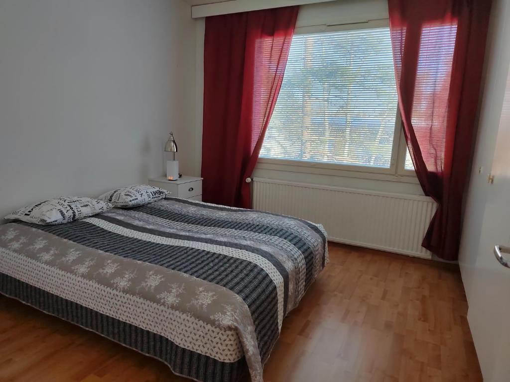a bedroom with a bed and a window with red curtains at Tampsan Lake in Kotka