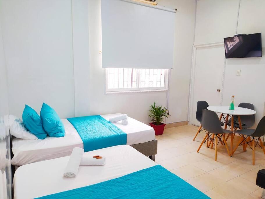 um quarto com duas camas e uma mesa e uma mesa em apartamento centro histórico 303-1 em Cartagena das Índias