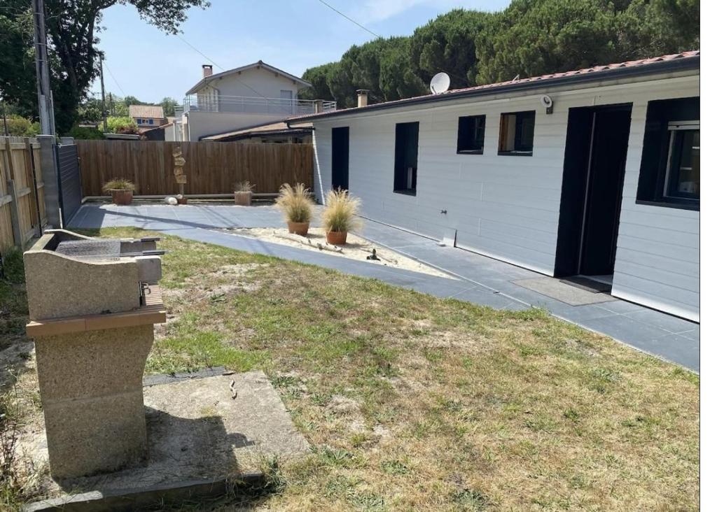 une cour avec une maison et quelques plantes dans l'établissement Biscarrosse Lac Maison au bord du canal pour 6 ou 7 personnes, à Biscarrosse