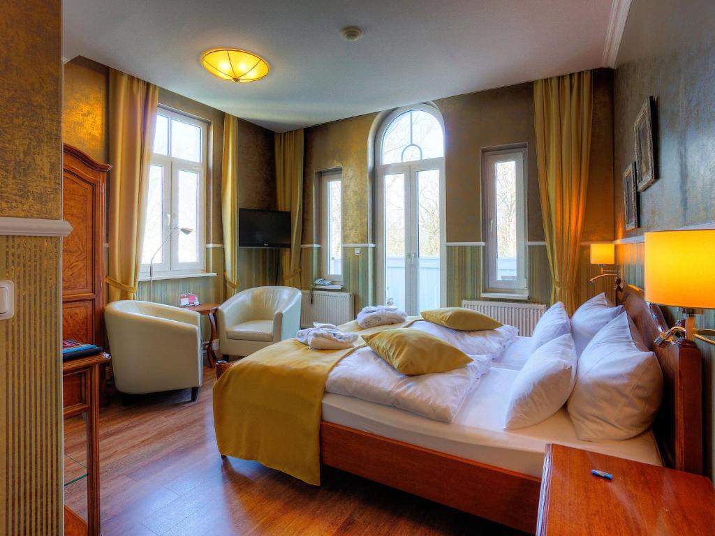 una camera con un grande letto in una stanza con finestre di KurparkHotel Warnemünde a Warnemünde