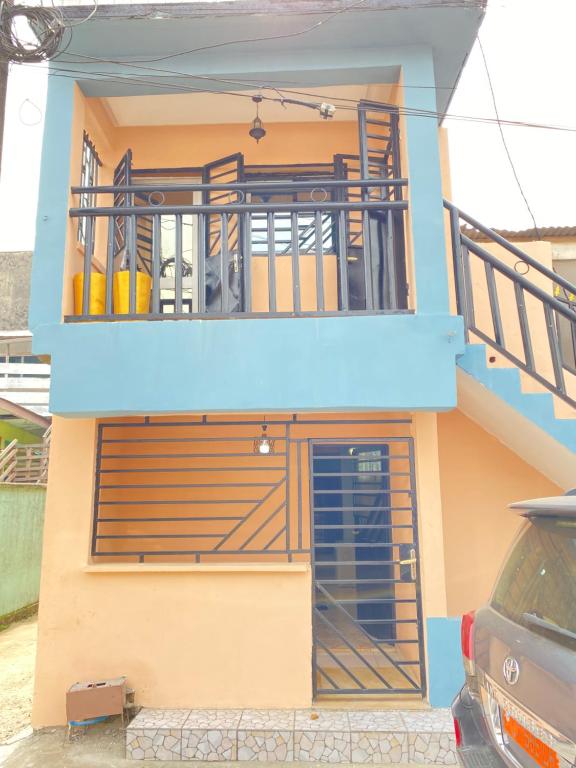 a house with a balcony and a car parked in front at N-E Studio meublé 2 in Douala