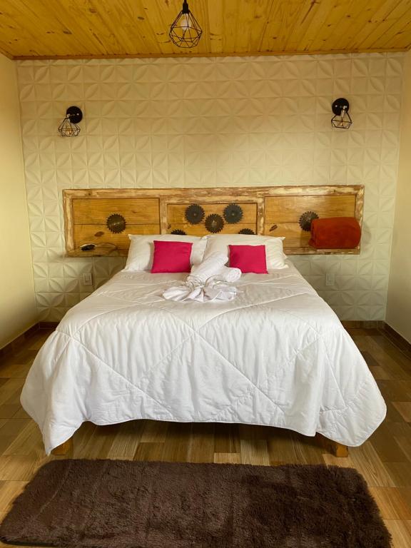 a bedroom with a white bed with pink pillows at Suíte Aconchego Mineiro in Ouro Preto