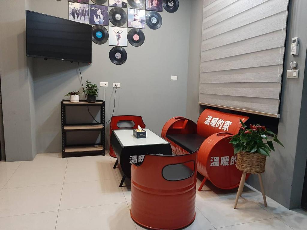 Hsia-san-chiehにある秧月民宿の赤い椅子、テレビ、テーブルが備わる客室です。