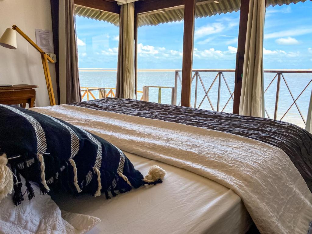 a bedroom with a bed with a view of the ocean at Santa Maria Atins in Atins