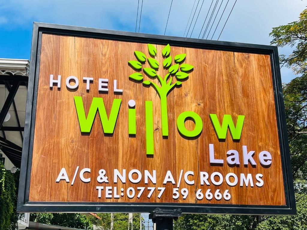 Hotel willow lake في كورونيغالا: علامة على بحيرة نافذة الفندق مع وجود شجرة عليها