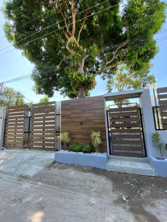 una recinzione di legno con un albero dietro di Cozy Grace Place a Orani