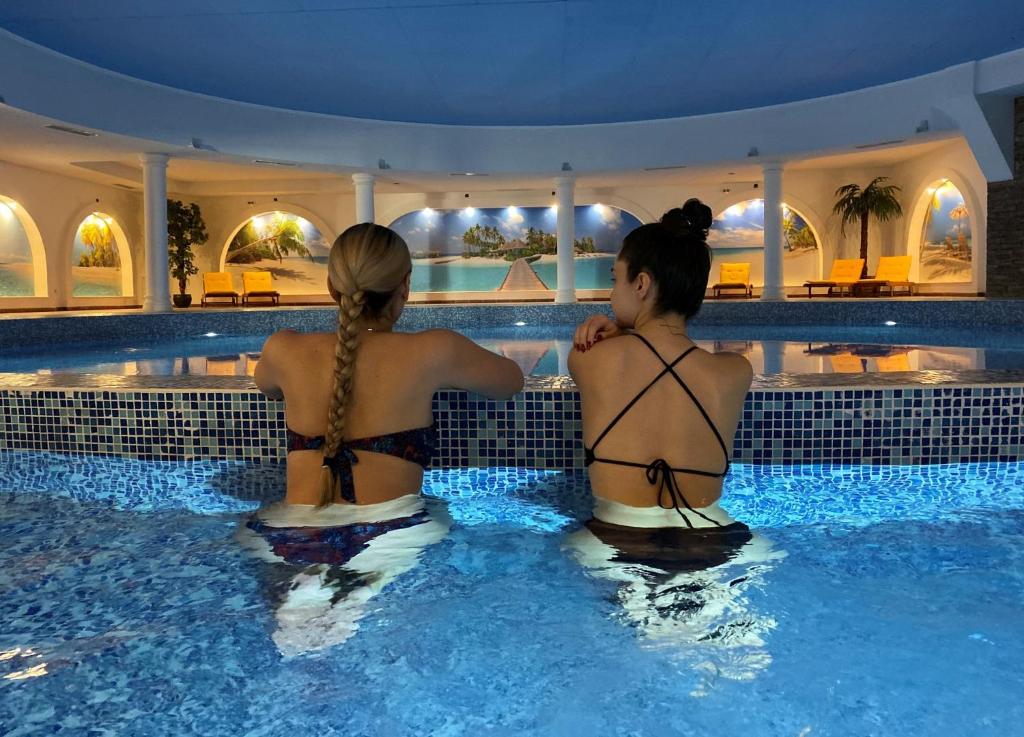dos mujeres sentadas en una piscina en Park Hotel Panorama en Bansko