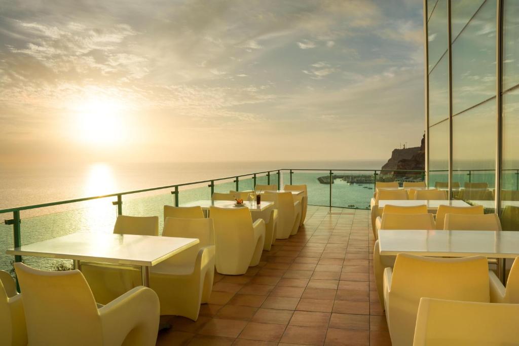 a balcony of a restaurant with tables and chairs at Mogan Princess & Beach Club in Taurito