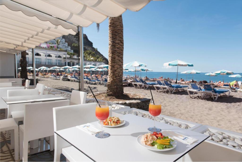 a table with food and drinks on the beach at Mogan Princess & Beach Club in Taurito
