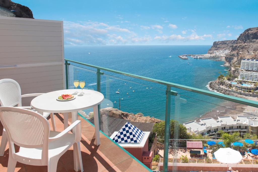 a balcony with a table and chairs and the ocean at Mogan Princess & Beach Club in Taurito