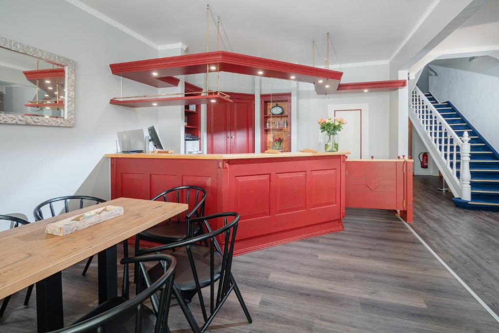 une cuisine avec des placards rouges, une table et des chaises dans l'établissement Hotel am Denkmal Norderney, à Norderney