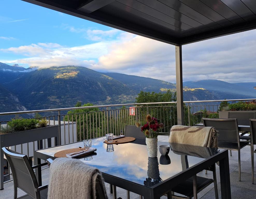 a table on a balcony with a view of mountains at Chalet Diognysos B&B, Boutique Hotel & Wellness in Crans-Montana