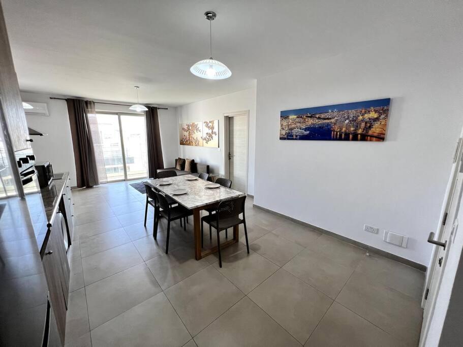 una sala da pranzo con tavolo e sedie in una stanza di Mediterranea 2 Bedroom Smart Apartment a San Pawl il-Baħar