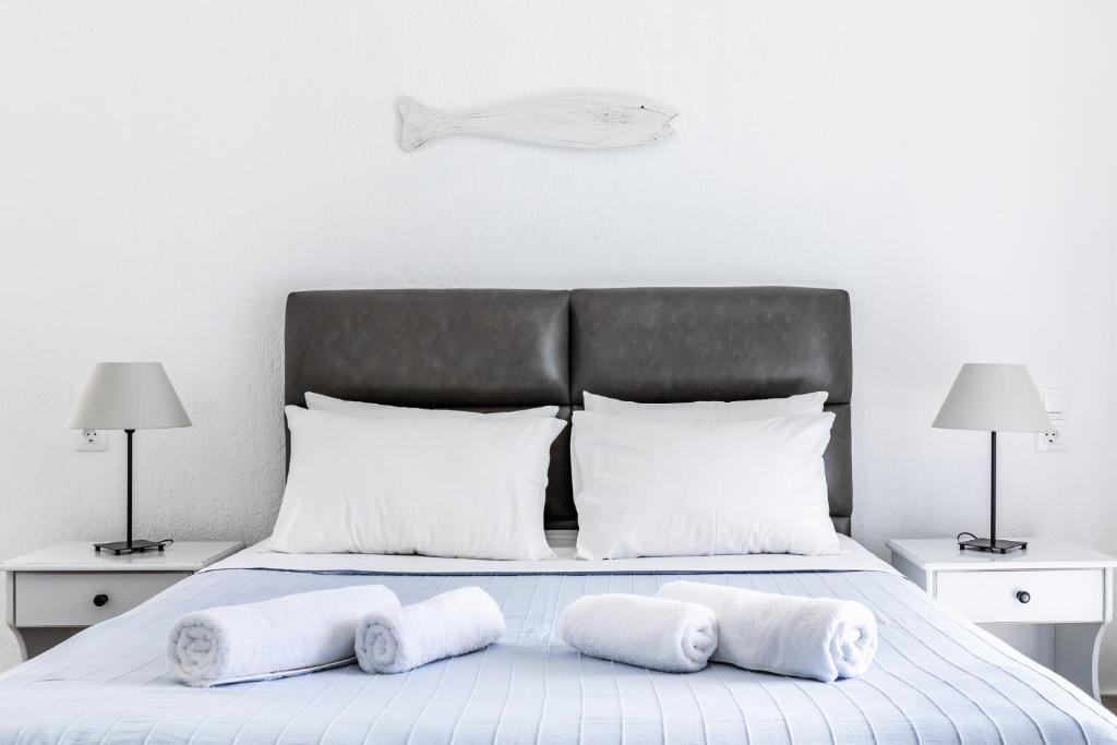 a bed with white pillows and a gray headboard at Milia Beach Apartments in Paralia Milia