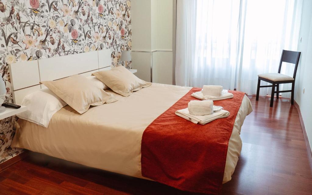 een slaapkamer met een bed met handdoeken en een stoel bij A Casa Antiga do Monte Apartamentos Turísticos - Pontecesures in Padrón