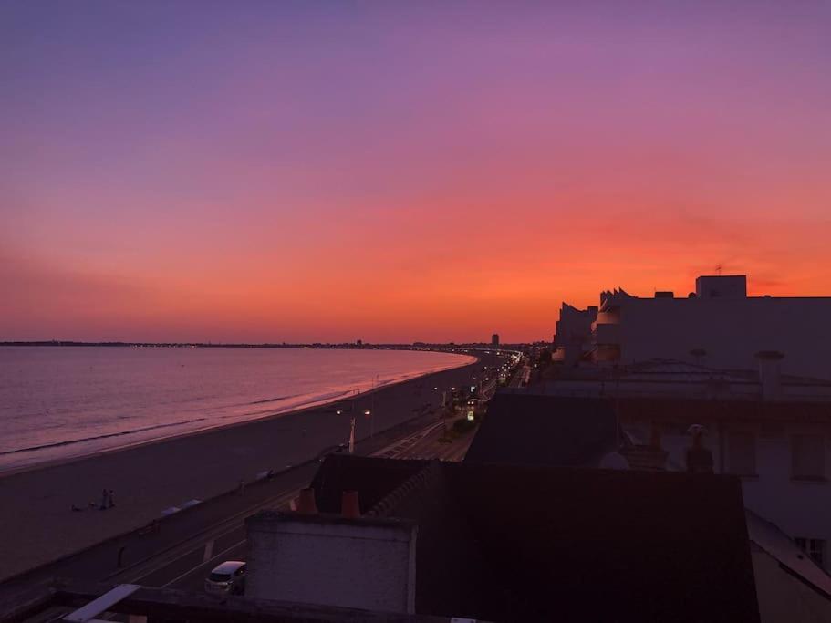 - un coucher de soleil sur une plage avec l'océan et les bâtiments dans l'établissement Magnifique Penthouse Pornichet, à Pornichet